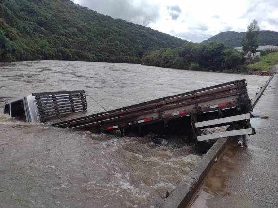 Caminhão cai de ponte, afunda na água e motorista se apoia em roda para conseguir sair
